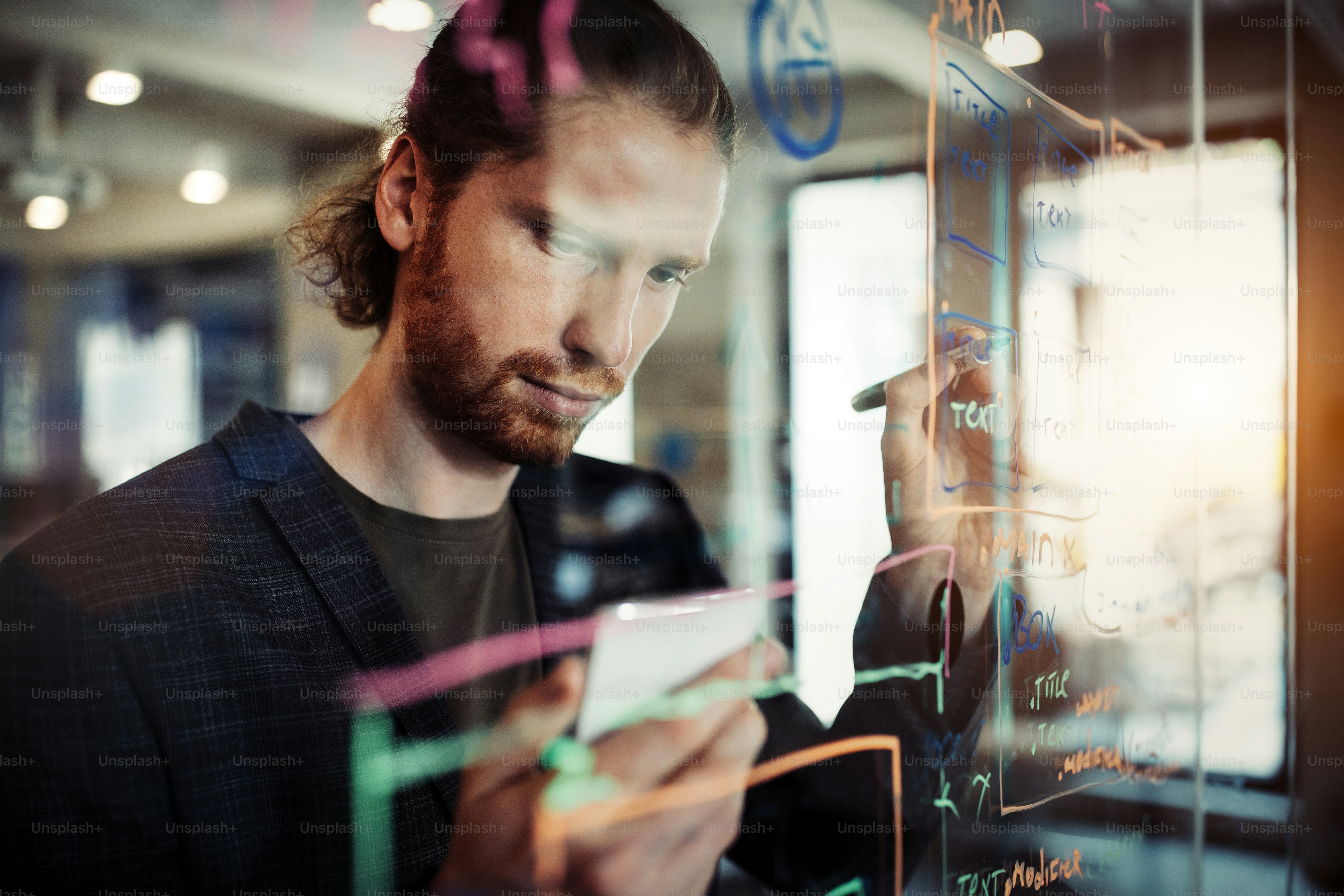 Man working and writing on the glass board in office. Business, technology, research concept