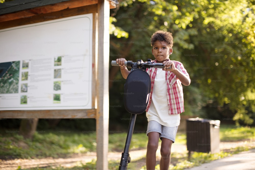 African American little boy riding electric scooter.