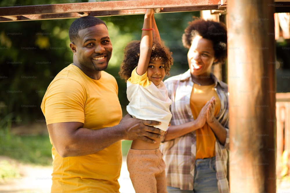 Familia afroamericana con un niño divirtiéndose al aire libre.