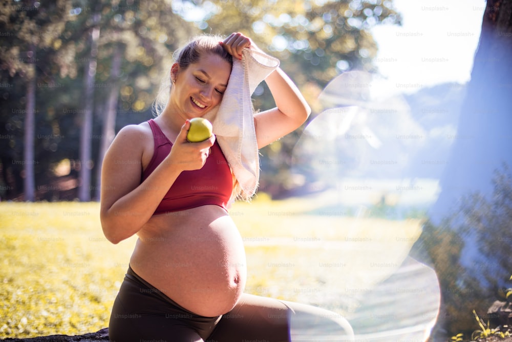Mujer embarazada comiendo ensalada después de hacer ejercicio en el parque.