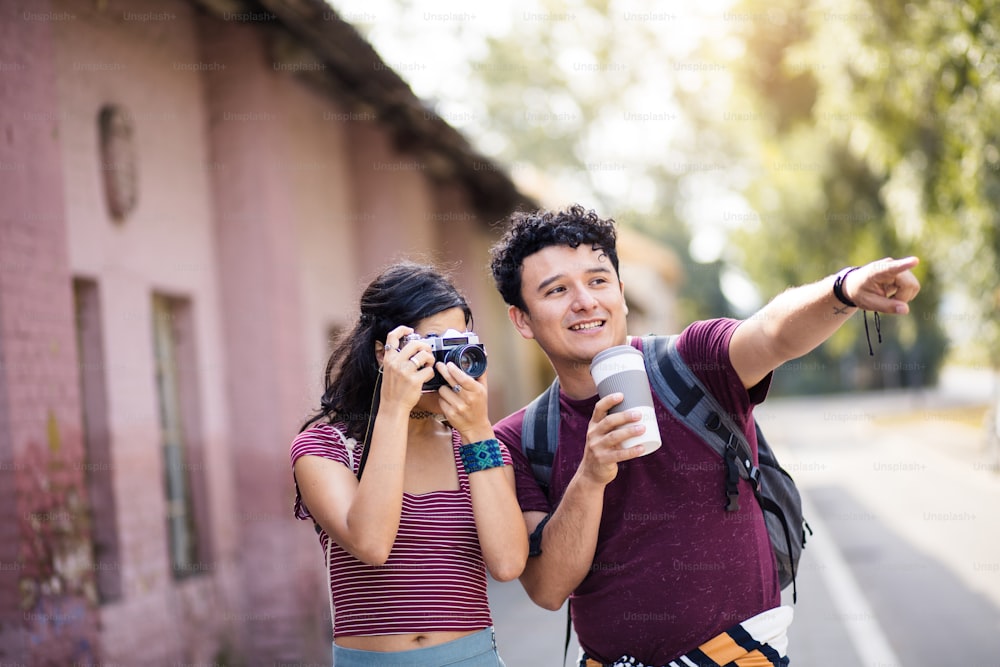 Young couple standing on street. Girl uses a camera.