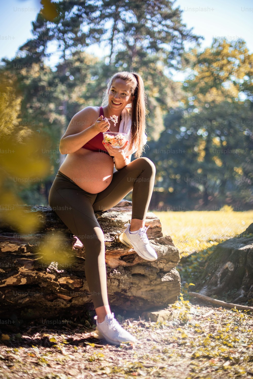 Donna incinta che mangia insalata dopo l'esercizio nel parco.
