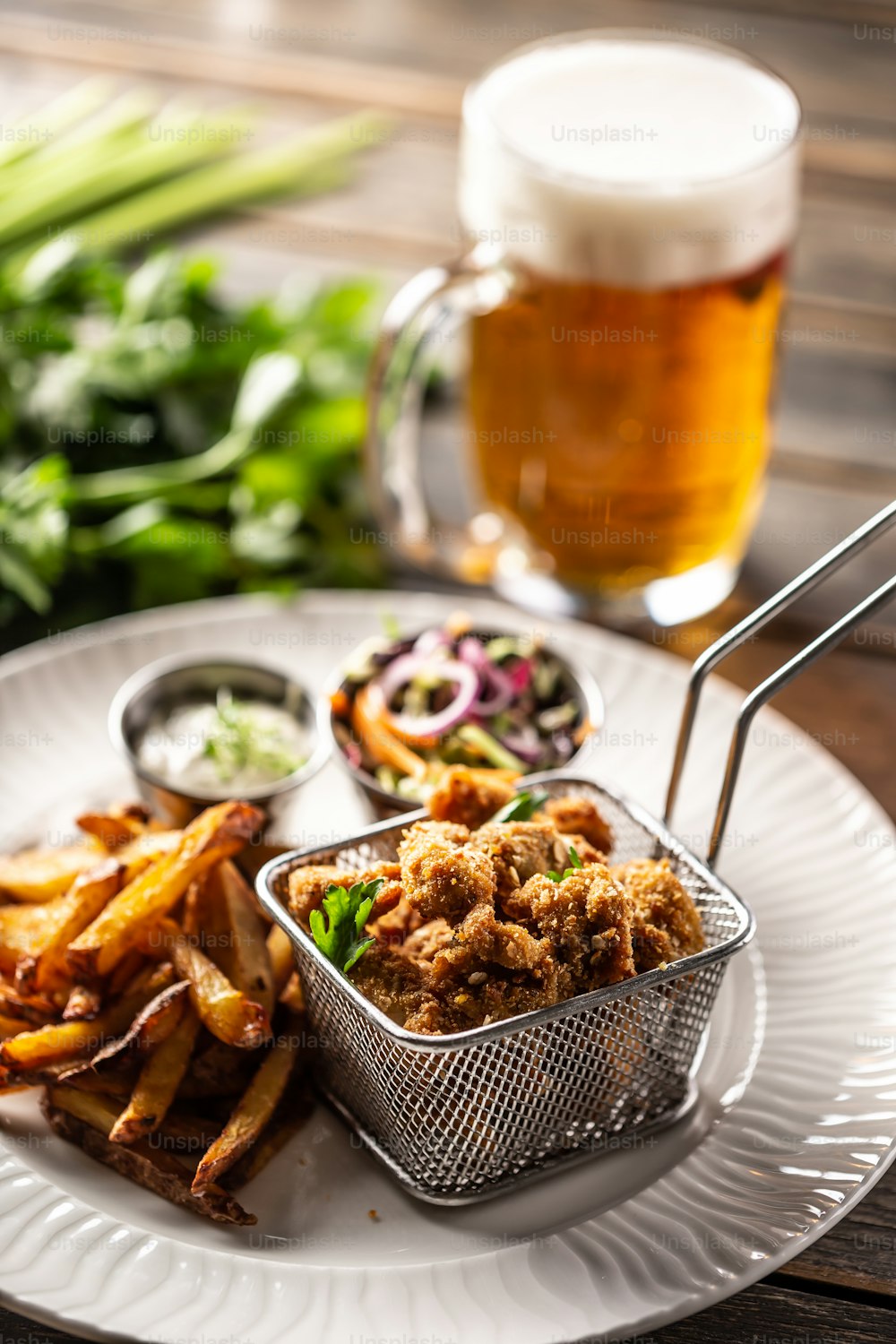 Fried chicken nuggets with french fries, dip, salad and beer.