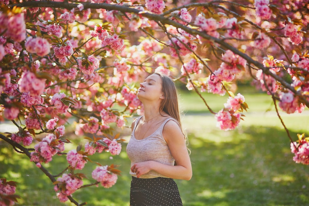 春の日の桜園の美しい女の子。フランス、パリ近郊の有名なソー公園の若い女性