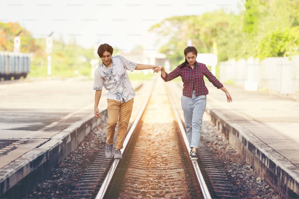 Young couple walking hand in hand on railway tracks, along railroad together