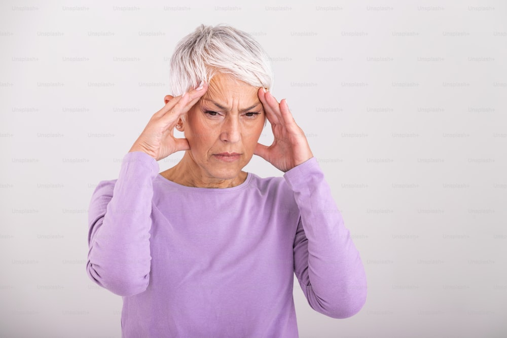 Attack of the monster migraine. Sinus pain. Unhappy Retired Senior Woman holding her head with pain expression . Face of senior woman suffering from headache