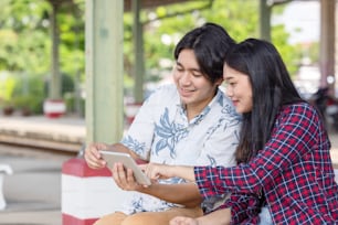 Young asian couple backpacker using tablet for find destination trip at railway station