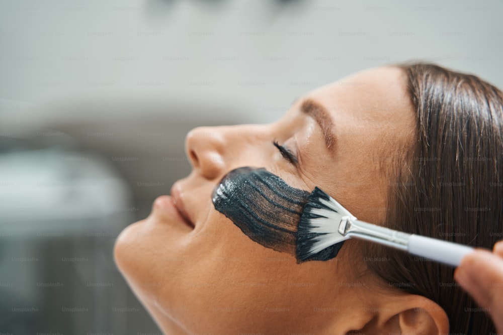 Nahaufnahmeporträt eines ruhigen Spa-Kunden, der sich während eines kosmetischen Eingriffs im Schönheitssalon entspannt