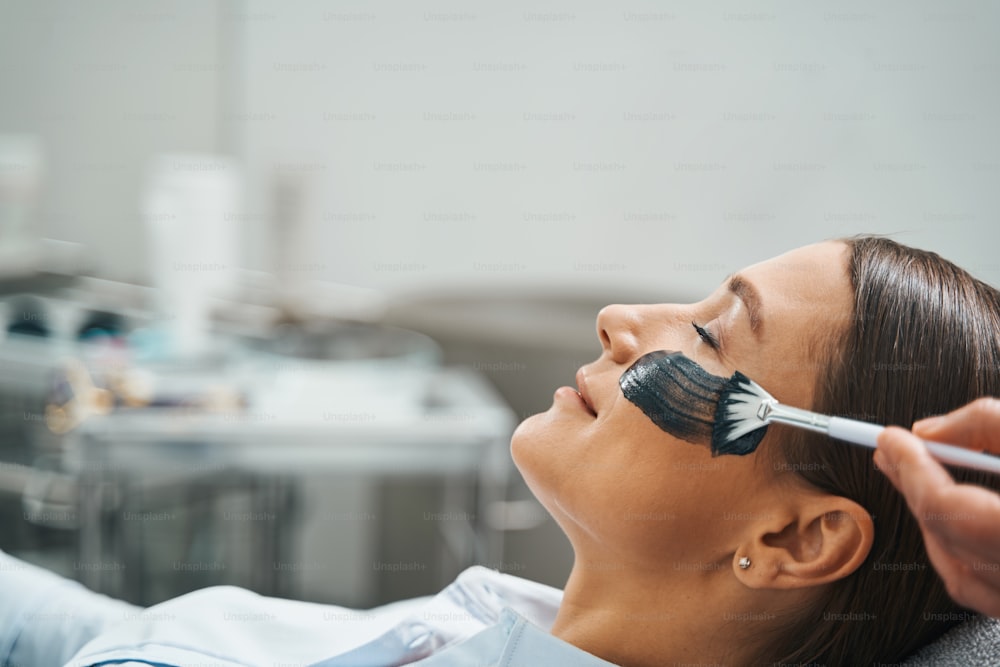 Side view of a tranquil young female patient napping in the dermatologist office during a beauty procedure