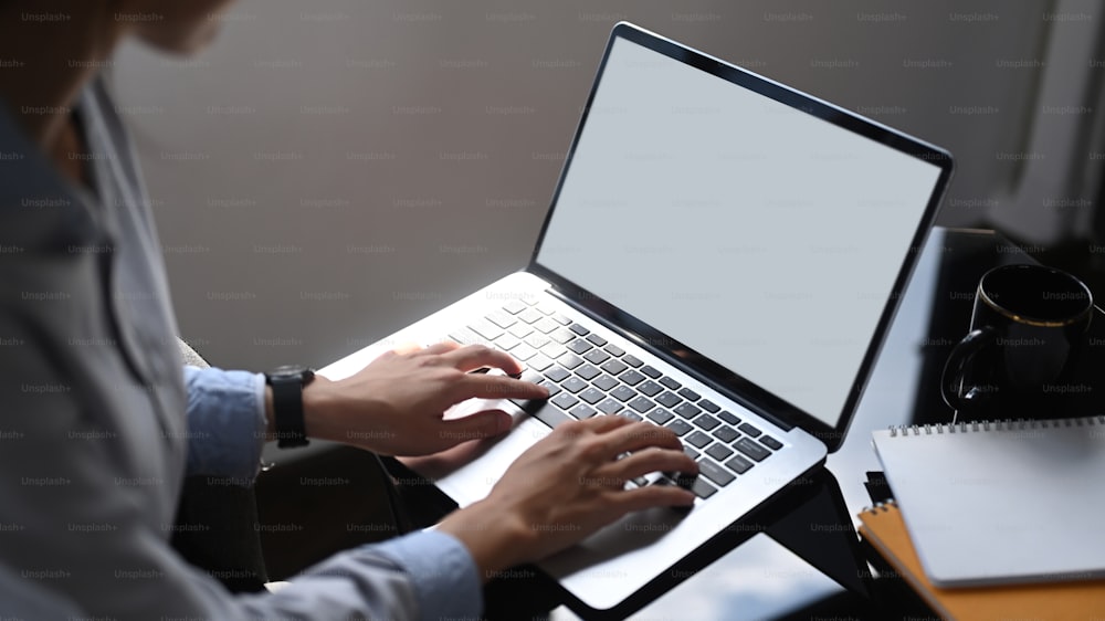 Ausschnittaufnahme einer Geschäftsfrau, die Informationen auf einem Laptop überprüft, während sie im Büro sitzt.