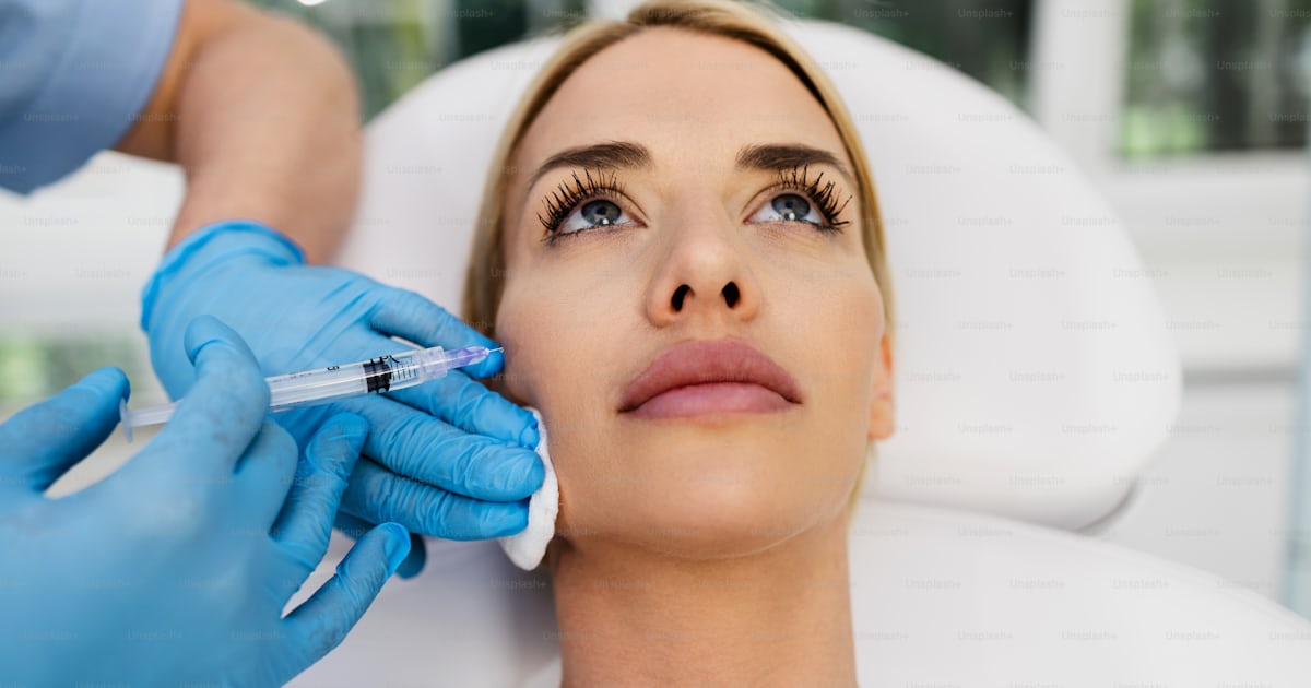 Attractive blond woman is getting a rejuvenating facial injections at ...
