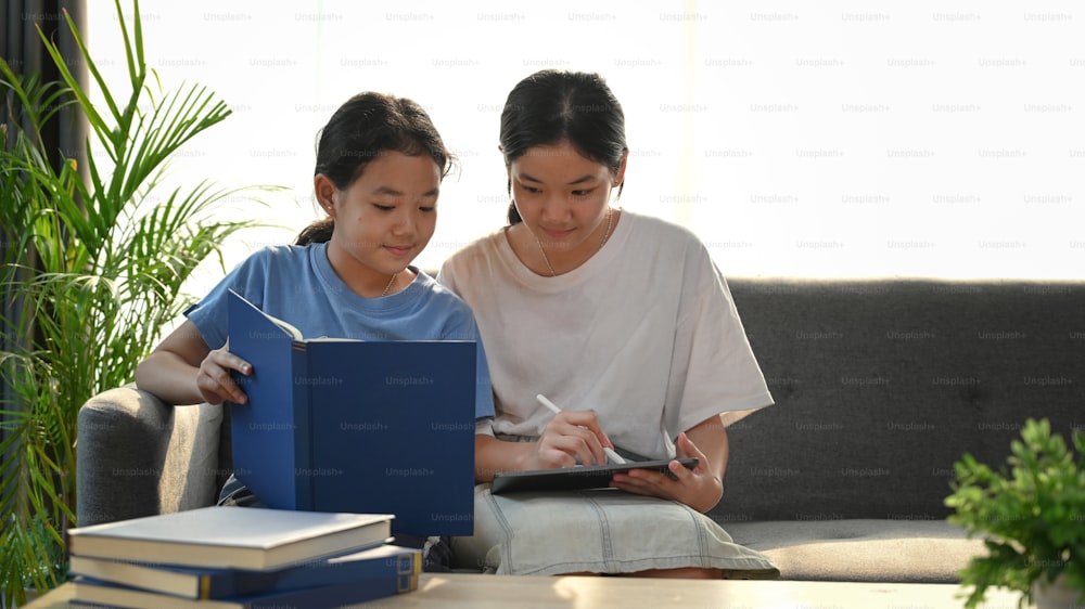Jovem asiática ajudando sua irmã fazendo lição de casa em casa.