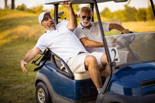 Deux amis plus âgés se promènent dans une voiturette de golf.