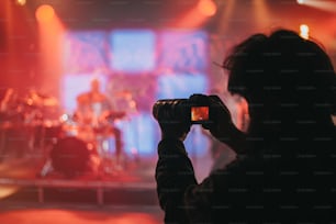 Silhouette di un fotografo che scatta foto di un musicista sul palco con le luci rosa durante il concerto in un festival