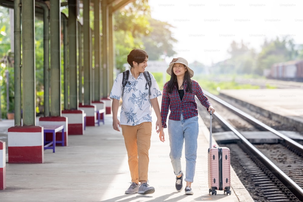 Uomo e donna con zaino in attesa del treno alla stazione ferroviaria. coppia amorevole viaggiatore viaggiare insieme in vacanza