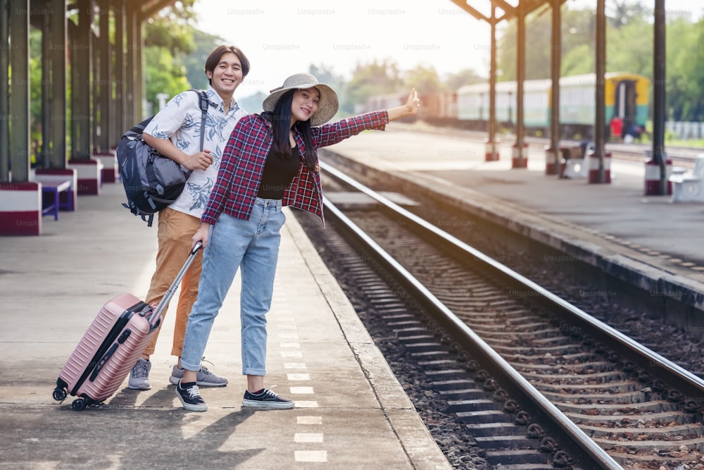 기차역에서 기차를 기다리는 배낭을 가진 남자와 여자. 사랑하는 커플 여행자는 휴가에 함께 여행합니다.