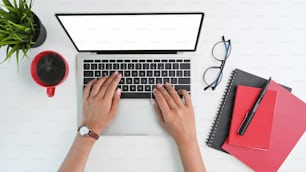 Top view workspace woman hands typing on mockup laptop computer with empty screen isolated display.