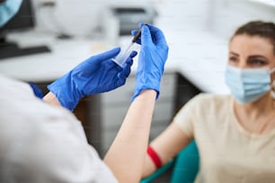 Técnico de flebotomia experiente montando a seringa na frente de um paciente jovem com uma máscara facial