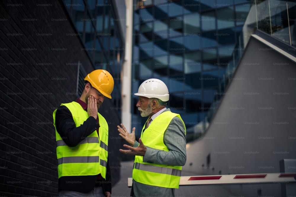 Frustrierender Arbeitstag. Reifer Ingenieur bespricht die Struktur des Gebäudes mit Architektenkollegen auf der Baustelle.