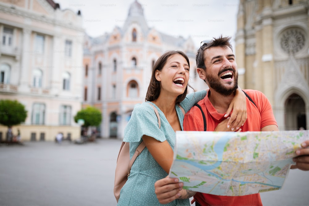 Sommerurlaub, Dating, Liebe und Tourismuskonzept. Lächelndes Paar zu Fuß mit Karte in der Stadt