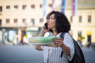 Tourist on street with map and talking on phone.