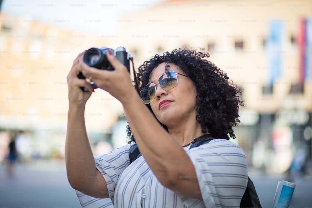Close-up image of urban female photographer using camera. Woman taking pictures in city.