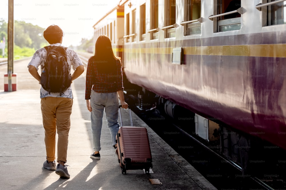 Uomo e donna con zaino in attesa del treno alla stazione ferroviaria. coppia amorevole viaggiatore viaggiare insieme in vacanza