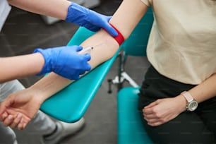 Foto recortada de uma enfermeira em luvas estéreis inserindo a agulha na veia do paciente