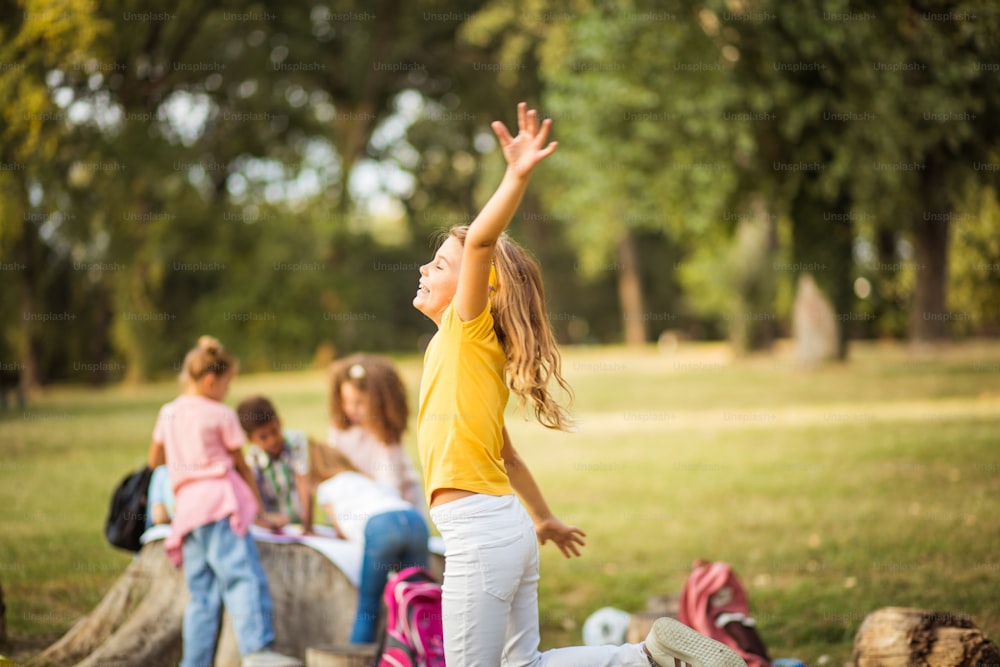 Large group of school kids in nature. Little girl dancing.