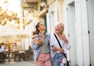 Two women on the street carrying books.