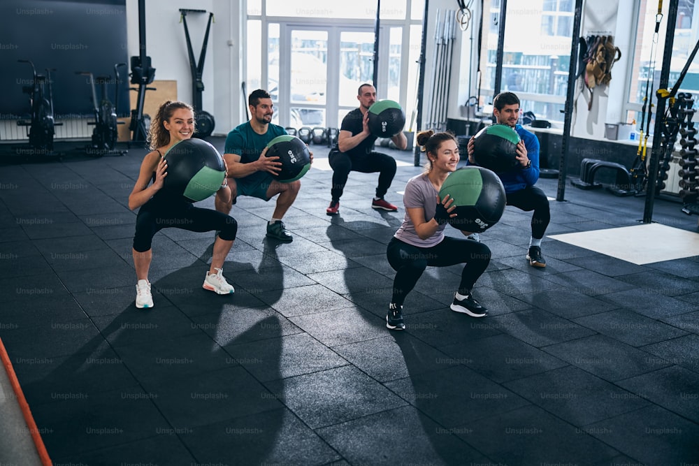 Grupo de cinco deportistas haciendo ejercicio junto con pelotas de estabilidad en un gimnasio