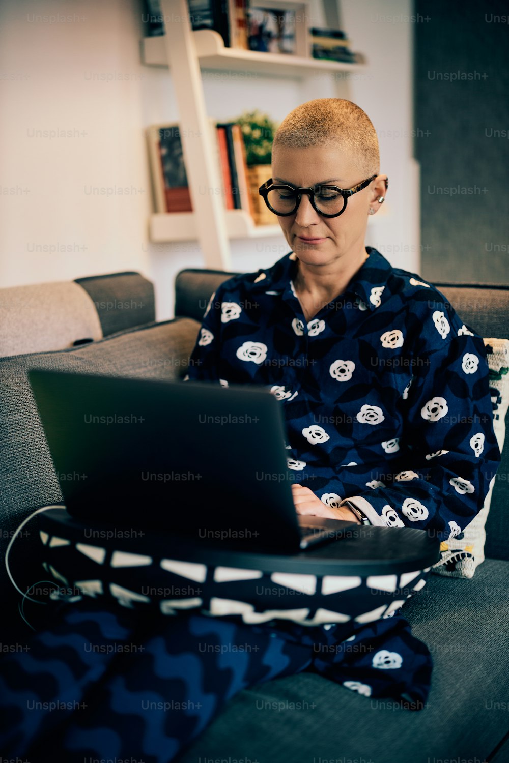 Attractive senior woman sitting on the couch at home and working on the project.