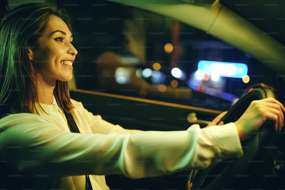 夜に車を運転しながら楽しんでいる幸せな女性。