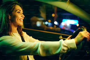 Mujer feliz disfrutando mientras conduce su coche por la noche.