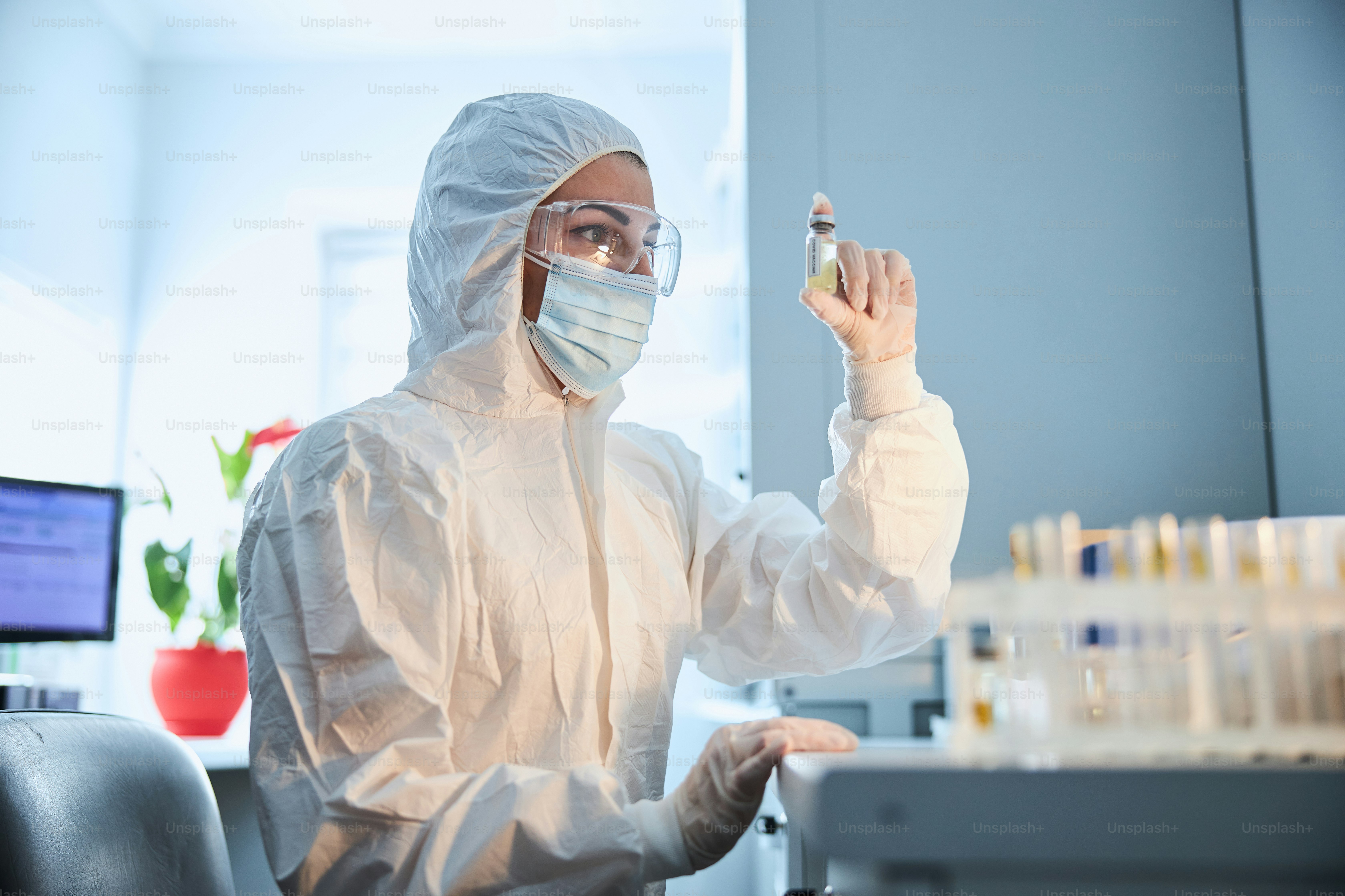 Scienziata seria con un farmaco antivirale in mano seduta al tavolo del laboratorio