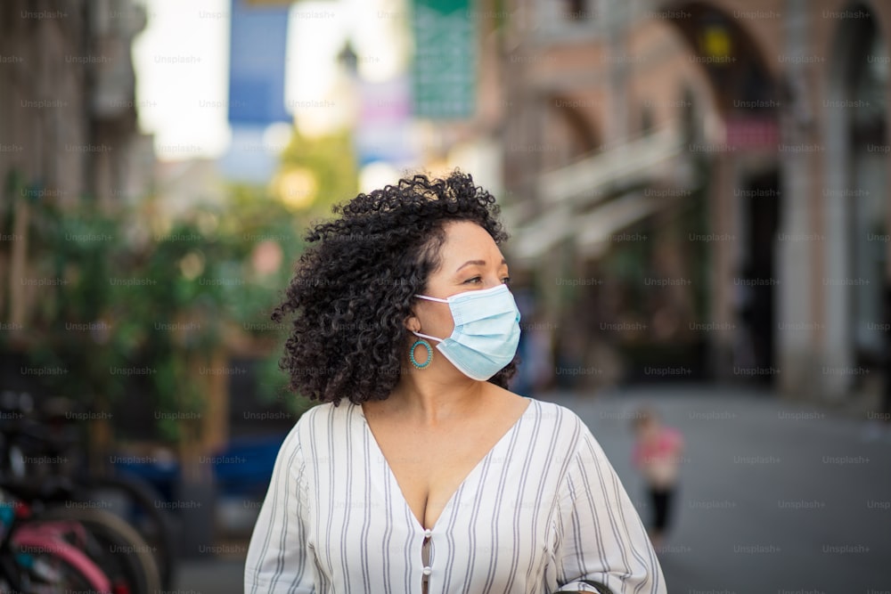 Woman with protective mask on face walking trough city.