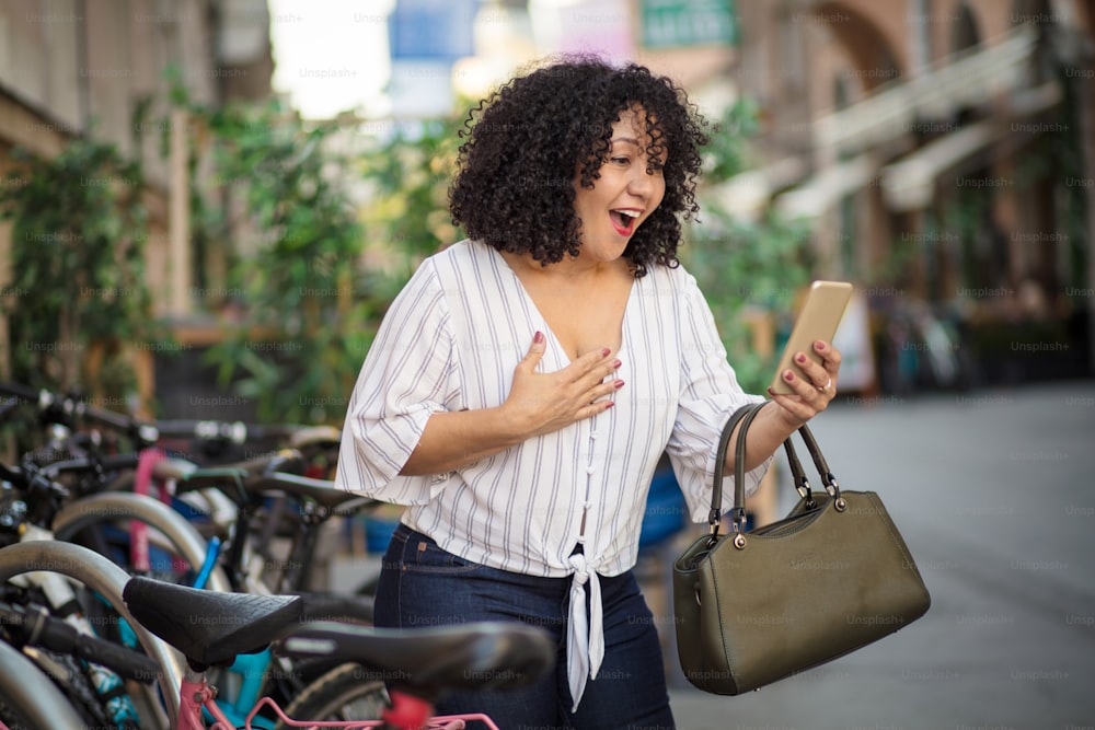 Appel vidéo.  Femme souriante debout dans la rue et utilisant un mobile.