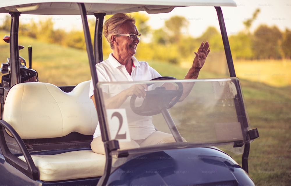 Happy Senior woman driving golf car.