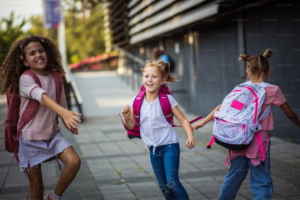 Crianças sorridentes voltando para casa depois da escola. As meninas da escola correndo no pátio da escola.