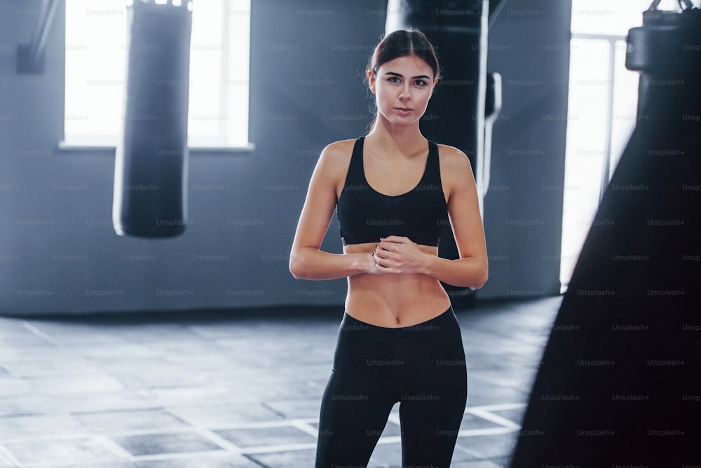 Una mujer joven con ropa deportiva está en el gimnasio haciendo ejercicio. Concepción del boxeo.