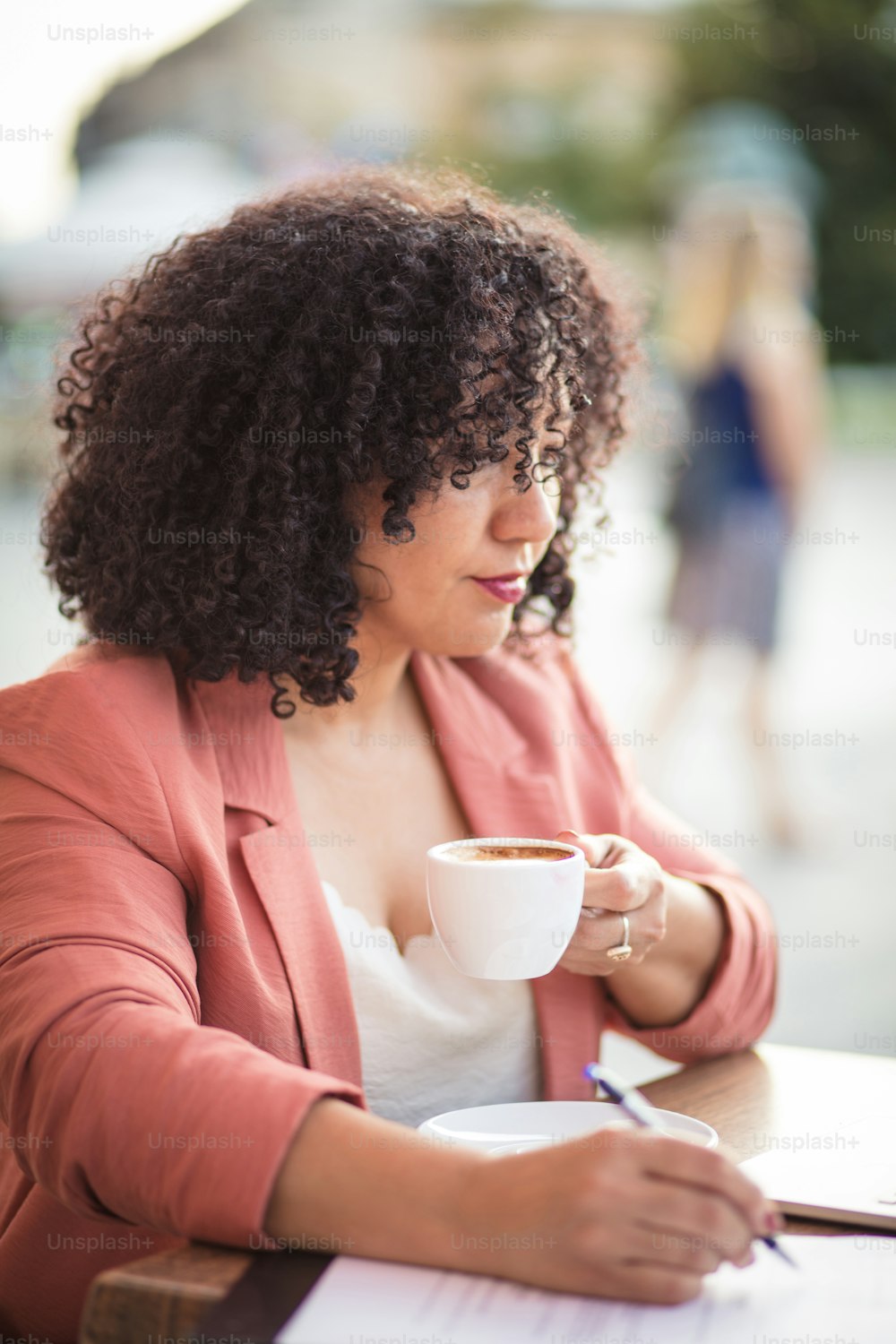 Femme d’affaires assise dans un café écrivant sur un document.