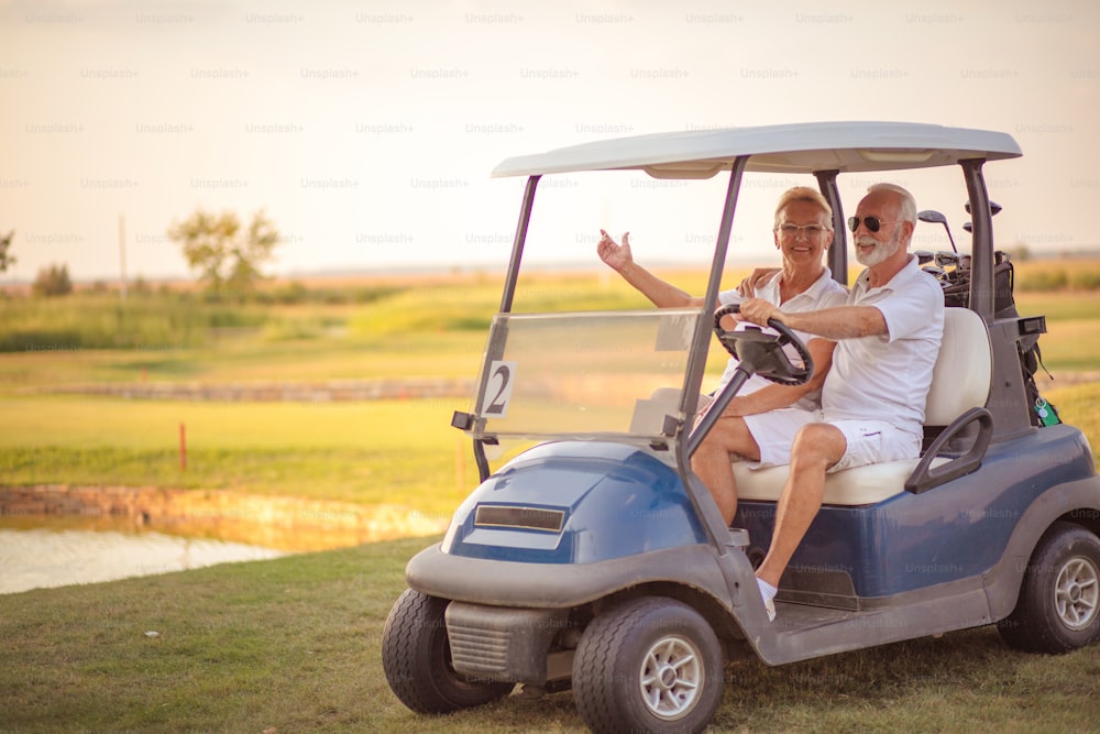 ゴルフカートに乗った年配のゴルフ夫婦。