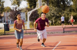 Giovane coppia che gioca a pallacanestro sul campo di strada.