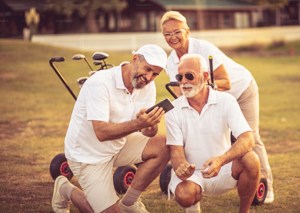 Senior golfers on court. Two men using smart phone.