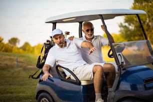 Dos amigos mayores viajan en un carrito de golf.