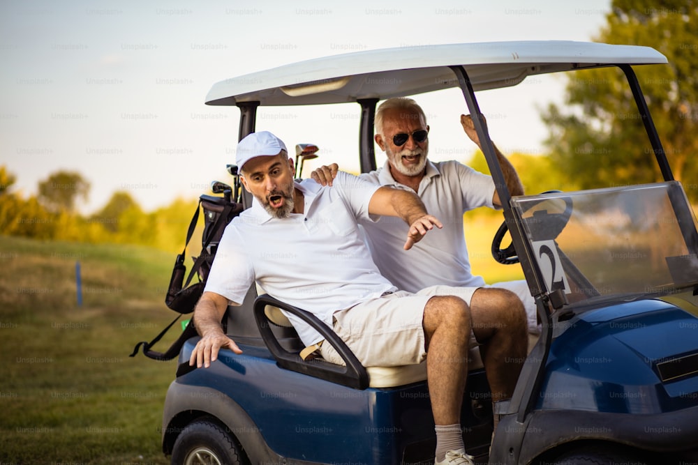 Dos amigos mayores van en un carrito de golf.