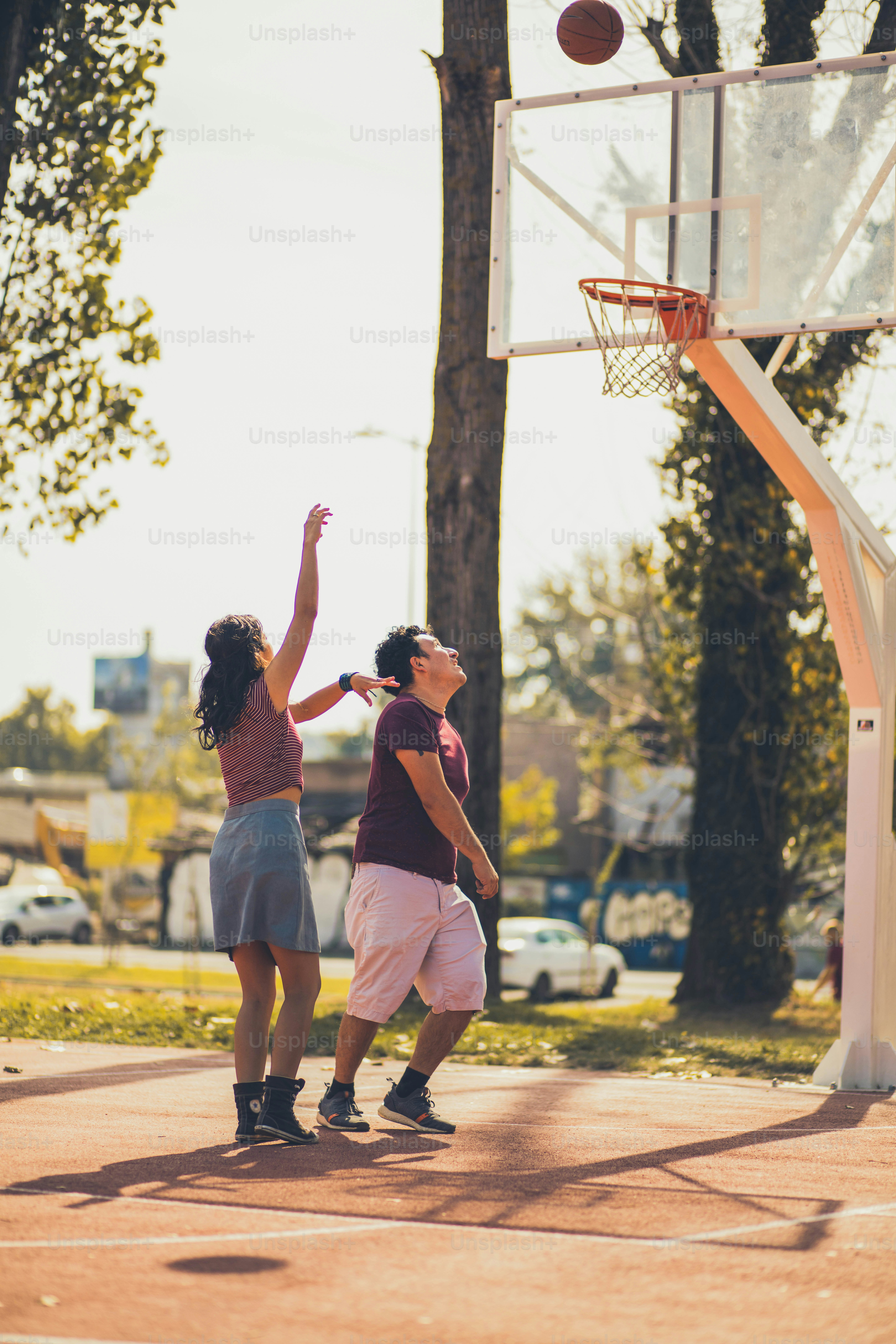 Pasangan muda yang bahagia bermain bola basket.