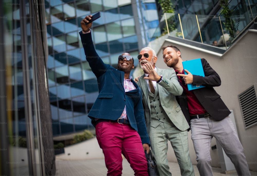 Three business men in the city. Man taking self portrait.