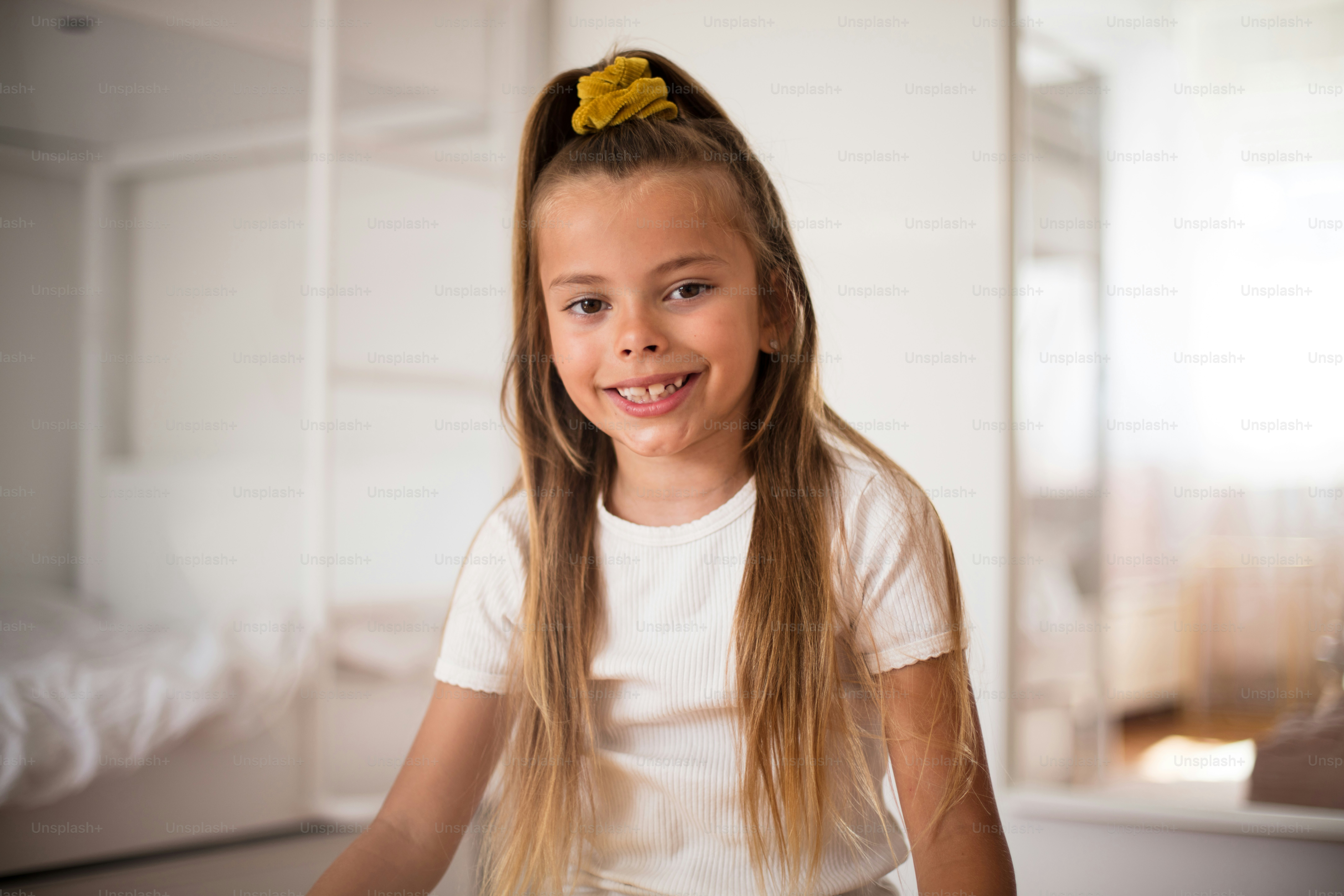 Smiling little girl in bedroom alone. Looking at camera.