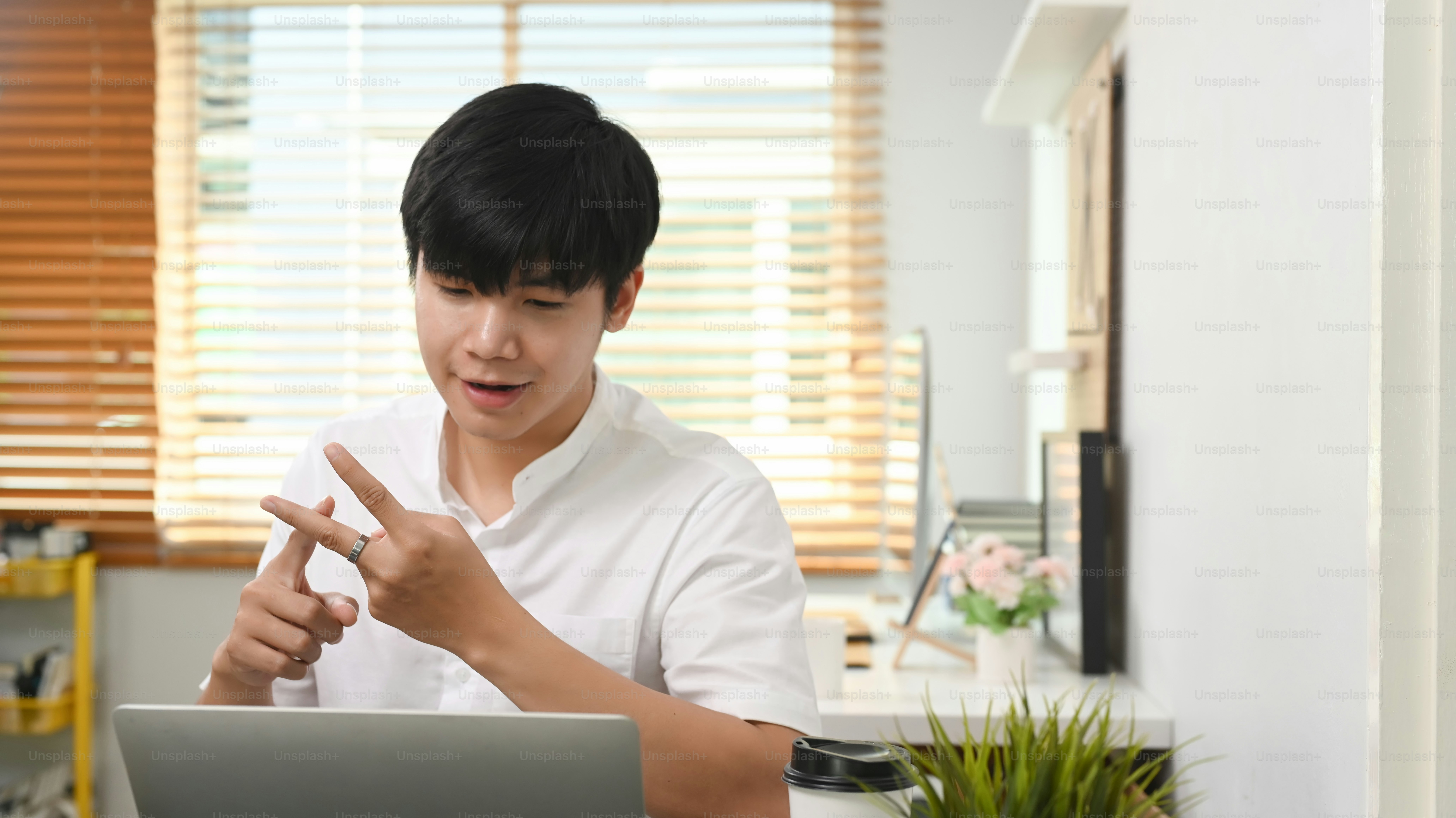 Young businessman having video call with business partner on laptop and discussing work project online.